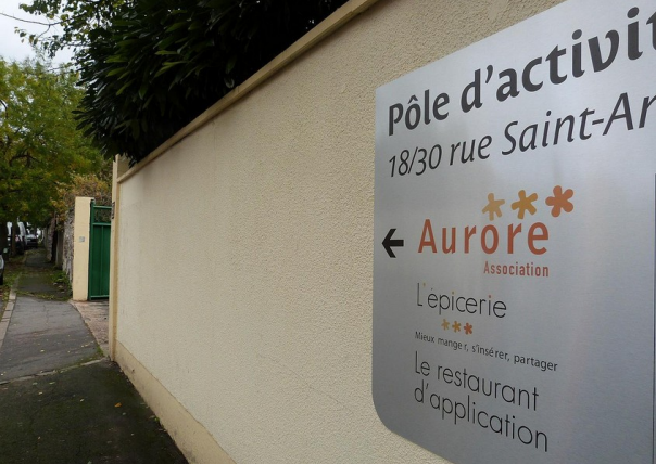 Mur avec un panneau écrit les infos relatifs à Aurore Solidarity Grocery